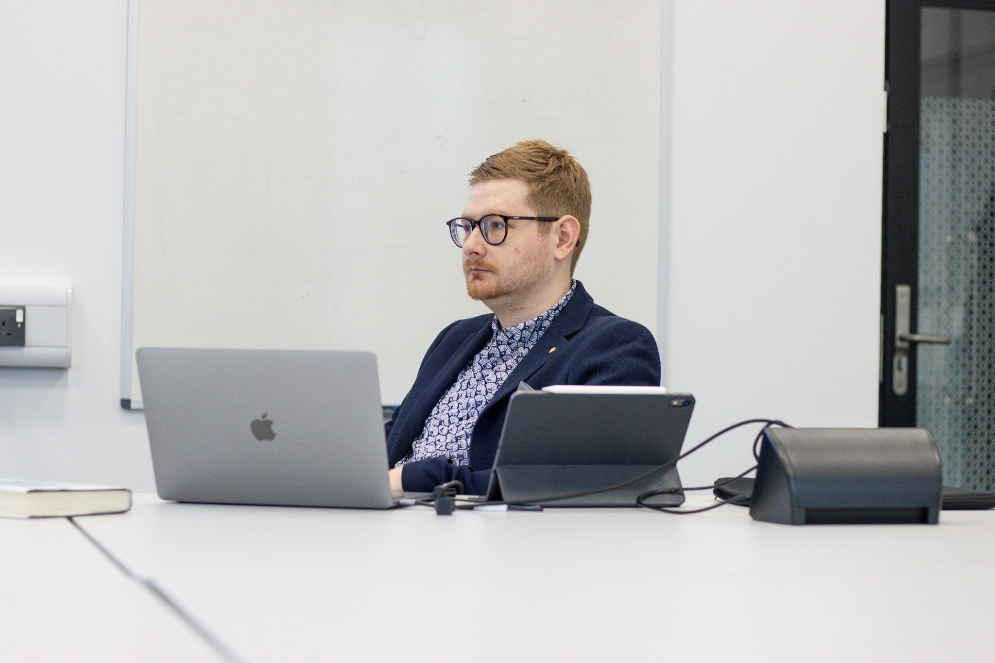 Tom Wardman working at a laptop in a client’s meeting room during a HubSpot planning session.