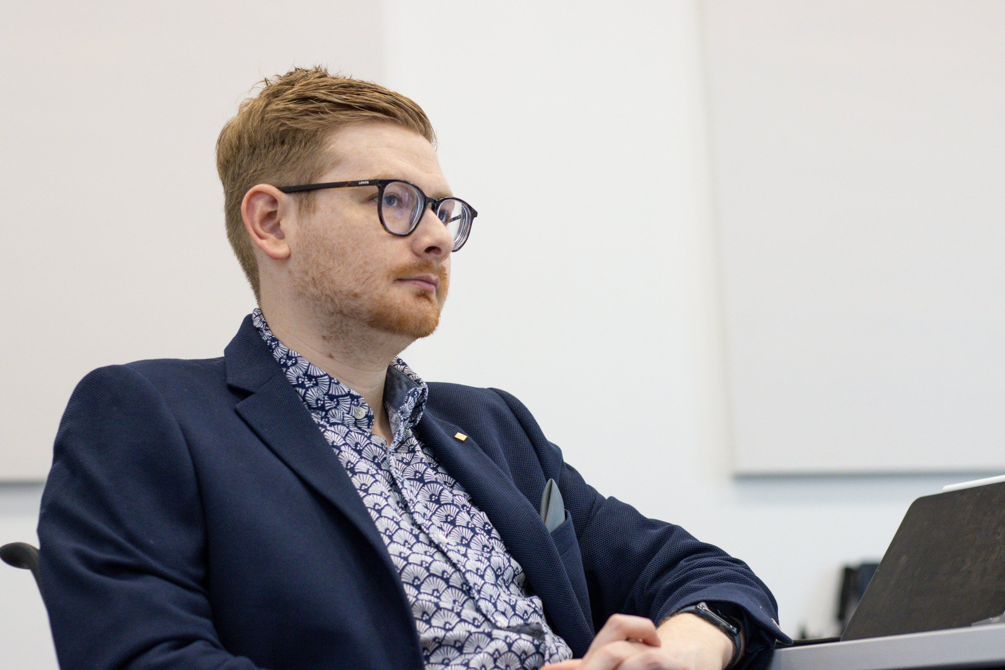 Tom Wardman sitting back at a client’s meeting table, smiling and relaxed as he listens.