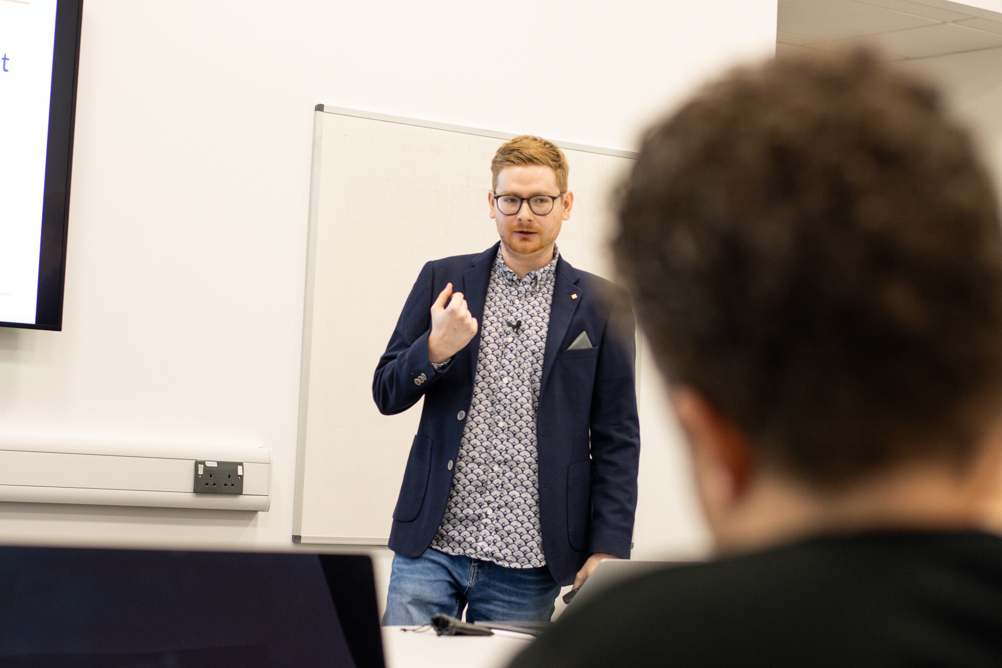 Tom Wardman presenting to a client’s leadership team, with an attendee listening in the foreground.